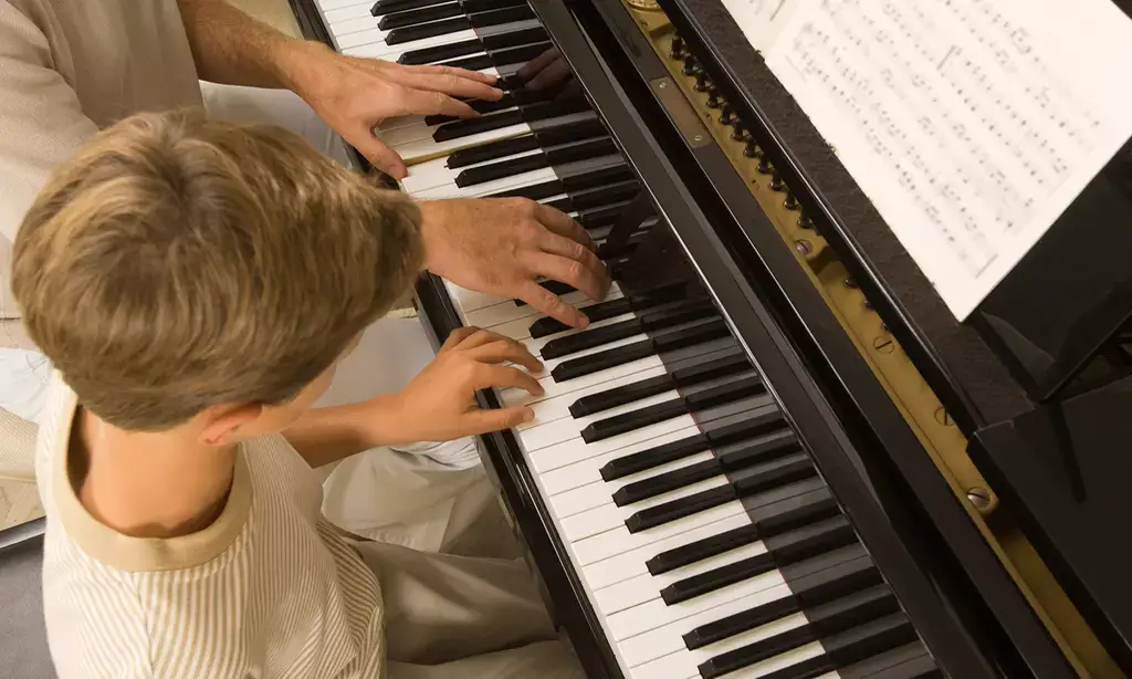 child playing piano with teacher